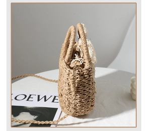 Detail view of woven straw beach bag featuring delicate white lace bow and drawstring liner