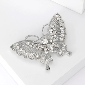 Detail of silver butterfly brooch featuring intricate rhinestones on a white podium