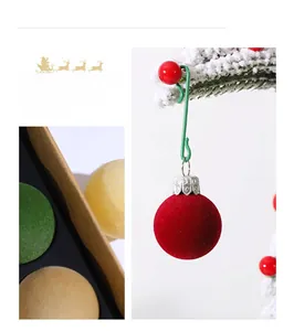 Close-up of 3cm flocked Christmas balls in red, green and yellow hanging on snowy pine twigs