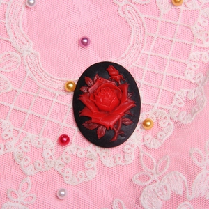 Vintage oval black resin pendant with red rose relief on pink fabric lace background