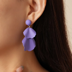 Close-up of a model wearing purple matte petal earrings with gold metal ring connectors