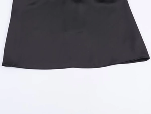 Detailed macro shot of the black satin fabric hem showing smooth texture and sewing craft
