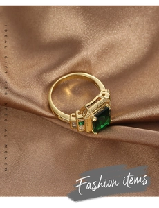 Close-up of a vintage brass ring with a square green zircon and beaded edge details