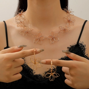 Detailed close-up of hollow gold woven floral necklace and earrings on a model