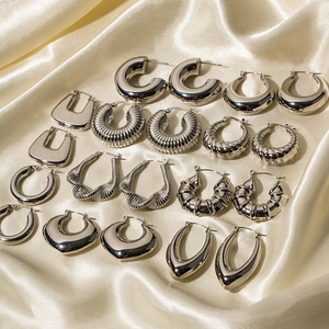 Set of 10 pairs of silver stainless steel geometric hoop earrings on silk fabric