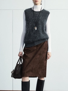 Detail view of brown faux suede midi skirt with front slit paired with a grey vest