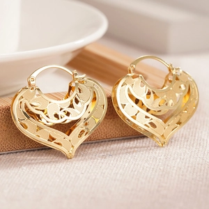 Macro shot of gold-plated hollow heart earrings with intricate floral carved patterns