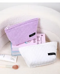 Macro detail of striped corduroy makeup bags showing brand label and zipper texture