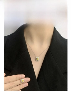 Detail of yellow gemstone necklace and earrings set on a model in a black suit