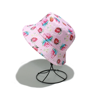 Detail of pink strawberry print bucket hat on display stand with canvas texture
