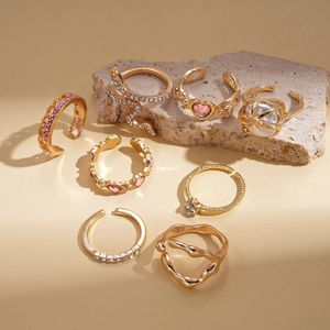 8pcs set of golden geometric heart rings with rhinestones and faux pearls on stone display