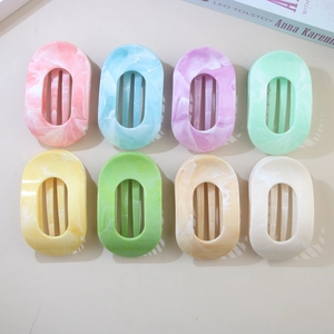 Flat lay of eight marble pattern ABS resin hair claws in various pastel colors on a table