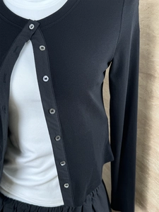 Detail of black long sleeve ribbed knit cardigan featuring delicate buttons and texture