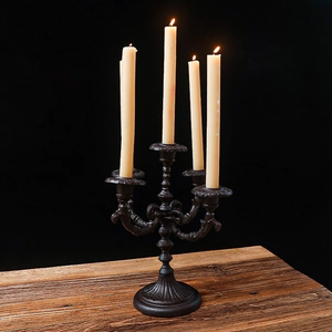 Classic vintage 5-arm iron candelabra with lit candles on a rustic wooden table