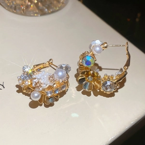 Macro shot of gold floral earrings with cluster pearls and iridescent crystals