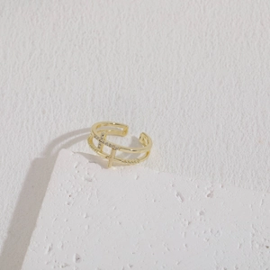 Close-up of golden double-layer cross ring with zircon stones on a stone stand
