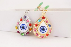 Close-up of teardrop evil eye charms in silver and gold with colorful crystals