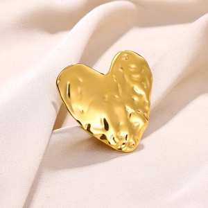 Textured gold heart ring with hammered lava finish on elegant beige pleated fabric