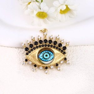 Detailed view of a gold-plated evil eye charm pendant featuring blue and clear zircon stones