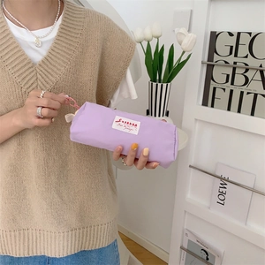Close-up of light purple nylon pencil case with woven label and pink plastic hook