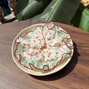 Sweet cherry print scrunchie with red plaid lace edge on a tropical leaf background