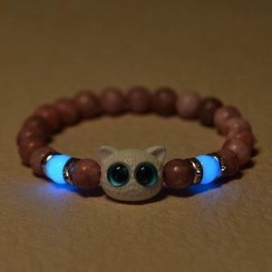Macro shot of luminous blue beads and white cat charm on natural stone bracelet