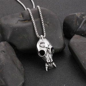 Close-up of vintage punk skull pendant with box chain on dark mystical stones