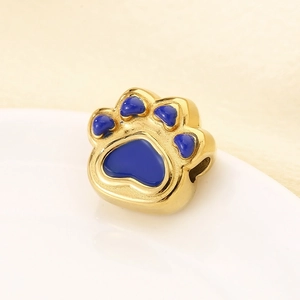 Macro detail of golden paw bead with blue enamel on a white ceramic plate