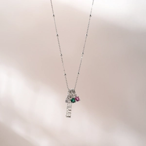 Detail of silver chain necklace with smile pendant, green and pink zircon stones