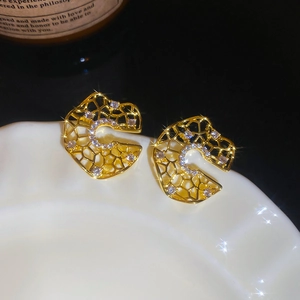 Detailed close-up of golden hollow C-shaped earrings with micro-pave cubic zirconia crystals