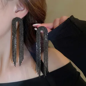 Long U-shaped black tassel earrings with sparkling rhinestones worn by a model