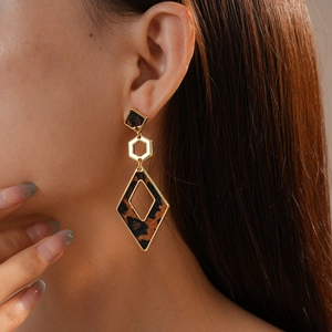 Close-up of geometric leopard print earrings with gold metal dangling on a model