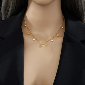 Elegant gold necklace with geometric crystals worn by a model on a black background