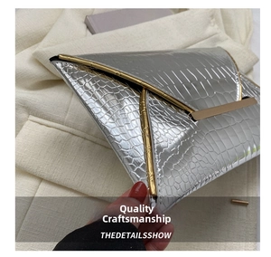 Detailed close-up of silver crocodile texture and gold metal trim on envelope clutch bag