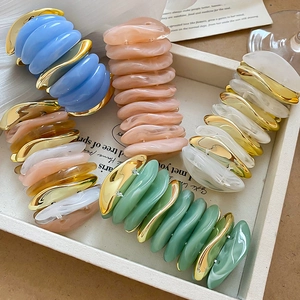 Detail of colorful acrylic pebble bracelets with marble texture and wavy gold metal links
