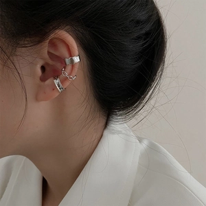 Close-up of three silver-toned ear cuffs featuring hammered metal and chain link textures