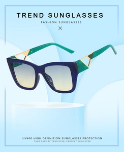 Detail of square cat-eye sunglasses with blue frames and green temples and gold metal accents