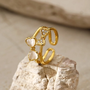 Detailed close-up of a double-layered gold ring with cat-eye heart stones and a bow
