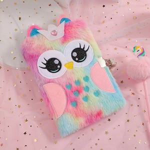 Detail of plush owl diary with lock, crown gem and unicorn pom-pom pen on pink tulle