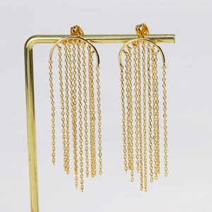 Detailed view of long gold tassel earrings hanging on a metal display stand
