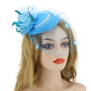 Close-up of blue fascinator hat with feathers, pearls and delicate mesh veil on a model