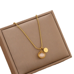Collier chaîne serpent dorée avec pendentifs en opale et métal sur boîte à bijoux brune