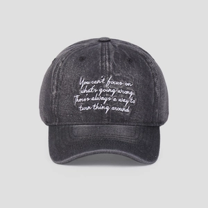 Détail de la broderie blanche sur une casquette de baseball en denim noir délavé vintage