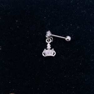 Macro view of silver crown ear piercing with sparkling zircon on black velvet