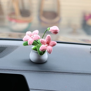 Close-up of pink plush sunflower car dashboard decor with white ceramic pot