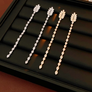 Detailed view of silver and gold tassel earrings with leaf design and zircon stones