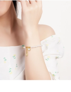Detail of freshwater pearl bracelet with gold shell and sparkling star charms on wrist