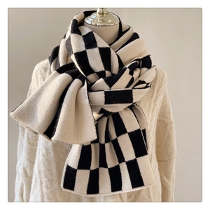 Detailed close-up showing soft knitted texture of black and white checkerboard scarf