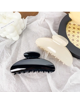 Close-up of elegant black and cream semi-circle hair claws on a minimalist background