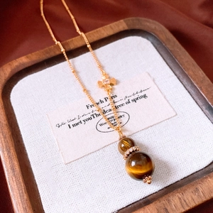 Macro detail of Tiger Eye gourd pendant necklace with gold chain and zircon inlay